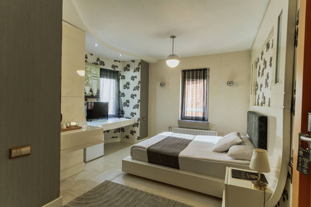 A modern bedroom with a bed, bedside table, and a desk area with a chair.
