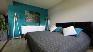 A modern bedroom with a large bed, teal walls, and a cityscape painting. - Fewo RheinDesign in Linz on the Romantic Middle Rhine with a beautiful river view (Linz am Rhein)