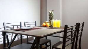 A dining table with chairs, a pineapple, oranges, and a glass of orange juice. - Two Bedroom Apartment at Koukaki (Athens)