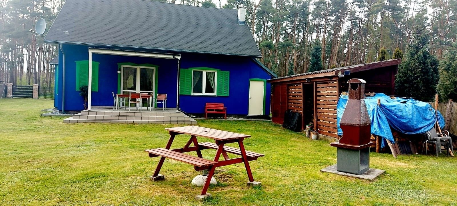 Een blauw huis met een terras, een barbecue en een picknicktafel.