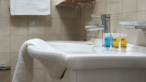 Ein Badezimmer mit einem weißen Waschbecken, einem Handtuch an der Wand und einem Ablagefach mit Toilettenartikeln.