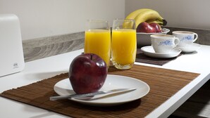 Ein Frühstückstisch mit einer Fruchtschale, zwei Orangensaftgläsern und einer Kaffeetasse.