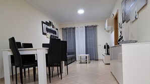 Una piccola cucina moderna con mobili bianchi, un tavolo da pranzo con sedie nere e un piccolo sgabello bianco.