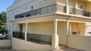 Un edificio su due piani con un balcone e un cortile in pietra.