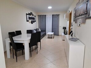 A modern living room with a dining table, black chairs, a white sofa, and a small white table. - ?salgados?golf?pool?wifi? Free ? 2BD (Albufeira)