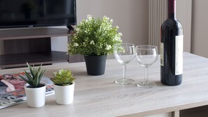 A wooden table with a potted plant, two wine glasses, and a wine bottle. - Zan Moreas A Simple & Minimal Apartment (Athens)