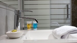 A bathroom with a white sink, a mirror, and toiletries. - Zan Moreas A Simple & Minimal Apartment (Athens)