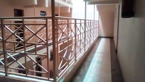 Un couloir agrémenté d’une grille en métal décorative, doté d’un sol carrelé et d’un escalier menant à un niveau supérieur.