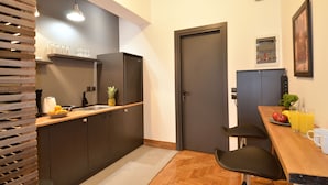 A compact kitchen with dark cabinets, a wooden countertop, a sink, and a small dining area with two chairs and a table.