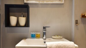 A bathroom with a white sink, a mirror, and a shelf with toiletries.