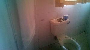 Un baño pequeño con inodoro, dispensador de papel higiénico y cortina de ducha.