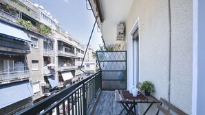 Ein Balkon mit Holztisch, einer Bank und einem Blumentopf.