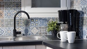 Eine Küche mit einem schwarzen Wasserhahn, einer Kaffeemaschine und zwei weißen Tassen auf der Arbeitsfläche.