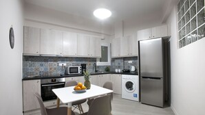 Eine moderne Küche mit Esstisch, Stühlen, einem Kühlschrank, einer Mikrowelle, einer Waschmaschine und einer gefliesten Spritzschutzwand.