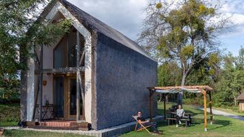 A small stone building with a sloped roof, a wooden pergola, and a picnic table.
