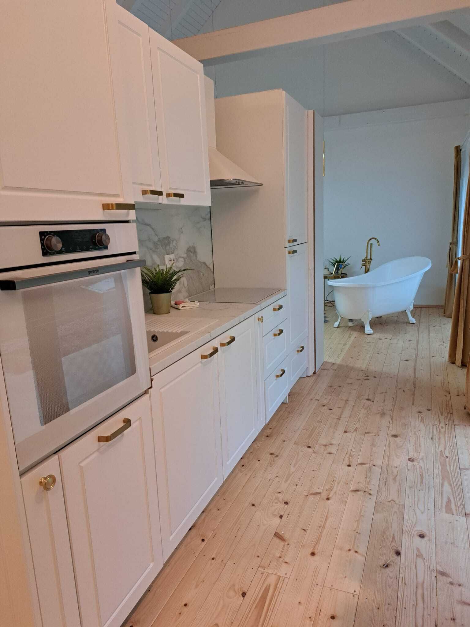 A modern kitchen with white cabinets, a built-in oven, and a marble backsplash.