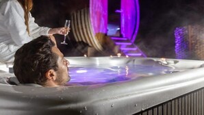 Un hombre se relaja en un jacuzzi mientras una mujer sostiene una copa de champán.