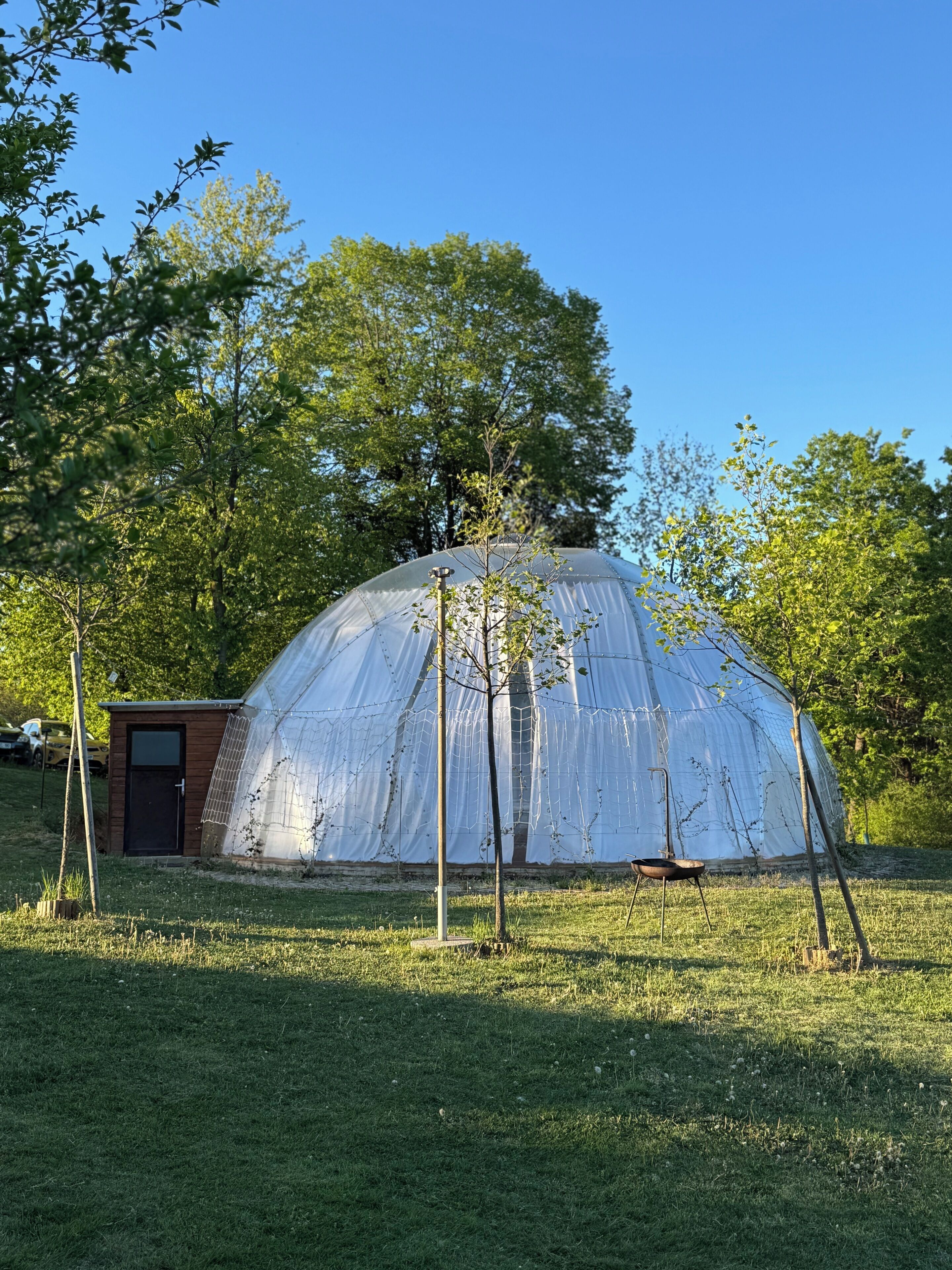A dome-shaped structure with a small attached building, surrounded by trees and grass.