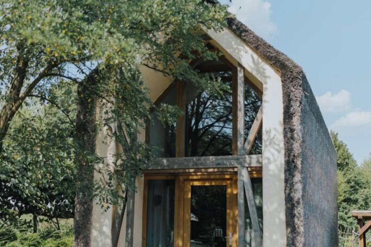 Une petite maison moderne, dotée d’un toit en pente, de grandes fenêtres et d’une entrée en briques.