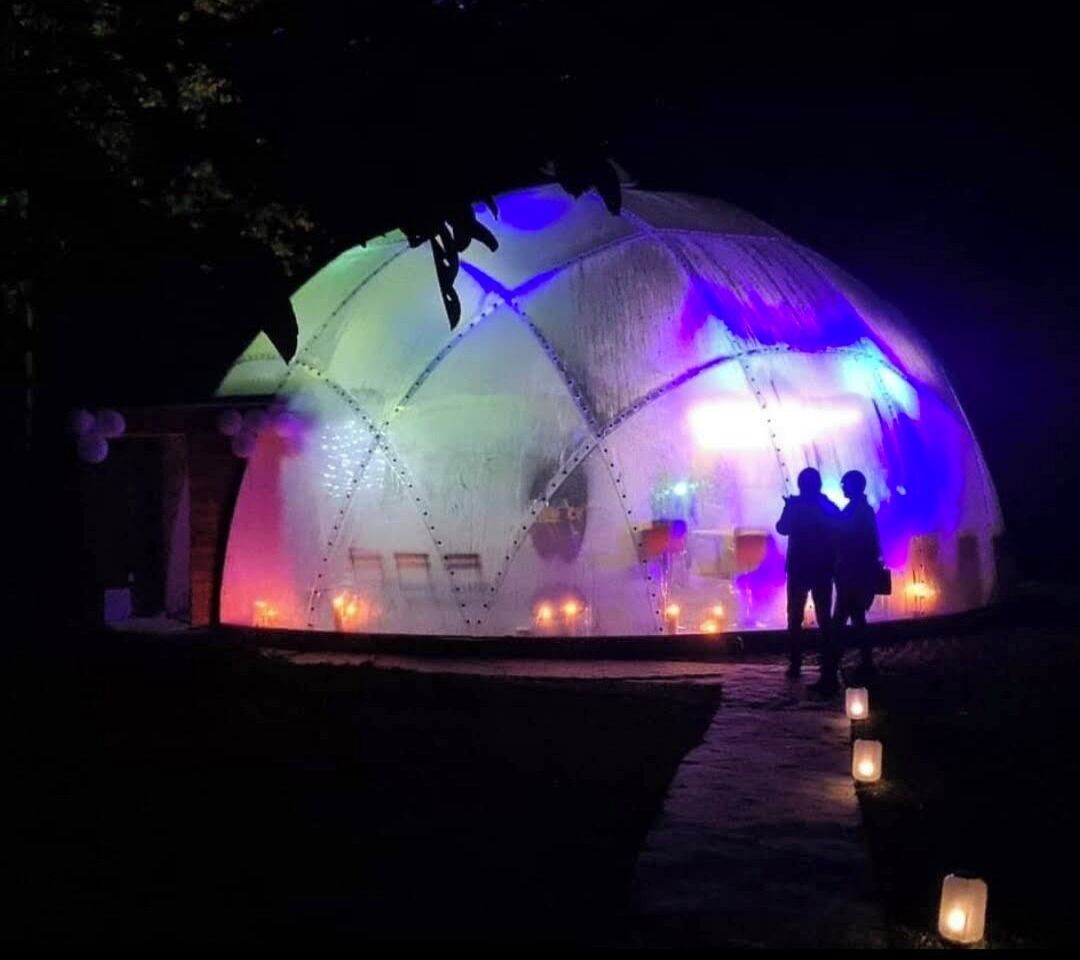 Una estructura en forma de cúpula con un sendero que la lleva a ella, iluminada por luces de colores.