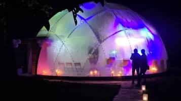 Una estructura en forma de cúpula con un sendero que la lleva a ella, iluminada por luces de colores.
