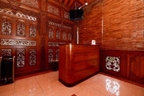 Un área de recepción con un mostrador de madera, paneles decorativos en la pared y un televisor montado en el techo.