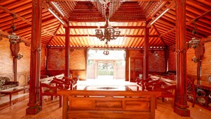 A traditional wooden interior with a central bench, ornate pillars, and a chandelier. - OYO 2327 Pagsis Village (Klaten)