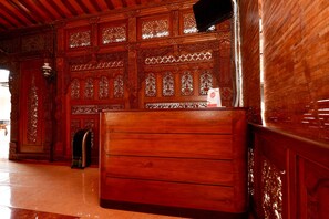 A wooden reception desk with intricate carvings and a tiled floor. - OYO 2327 Pagsis Village (Klaten)