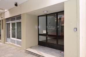 Entrada de un edificio con puerta de cristal y ventana con reja de metal.
