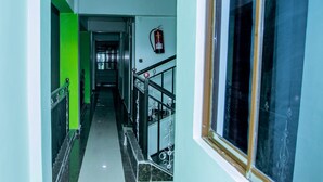 A hallway with a green accent wall, a fire extinguisher mounted on the wall, and a window with a decorative frame. - Moonshine Walkers (Eldoret)