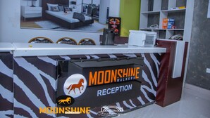A reception desk with a zebra print design, a framed image of a bedroom, and a white cabinet with shelves. - Moonshine Walkers (Eldoret)