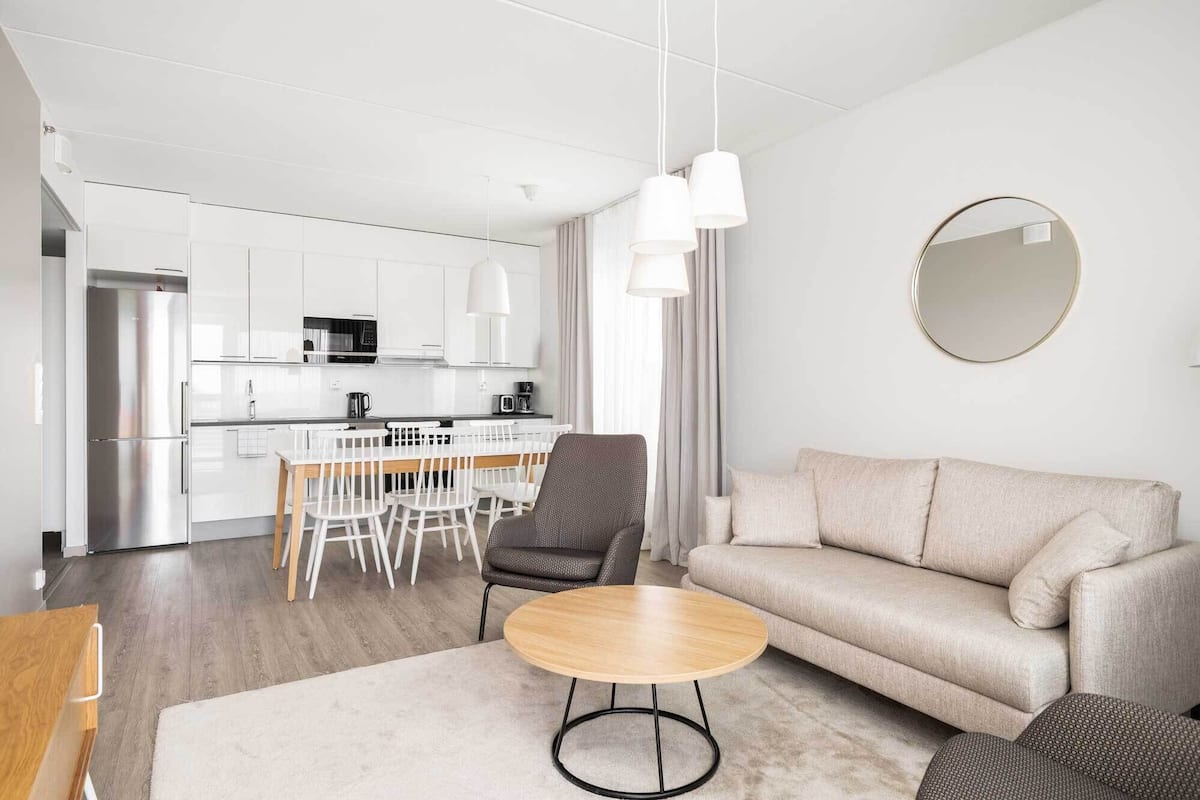 A modern living room with a sofa, a round coffee table, and a dining area with chairs and a table.