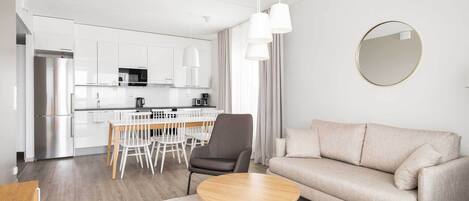 Una sala de estar moderna con un sofá, una mesa de centro redonda y un comedor con sillas y una mesa.