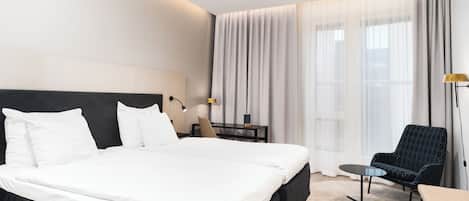 Una habitación de hotel moderna con una cama grande, un escritorio, una silla y una mesita.
