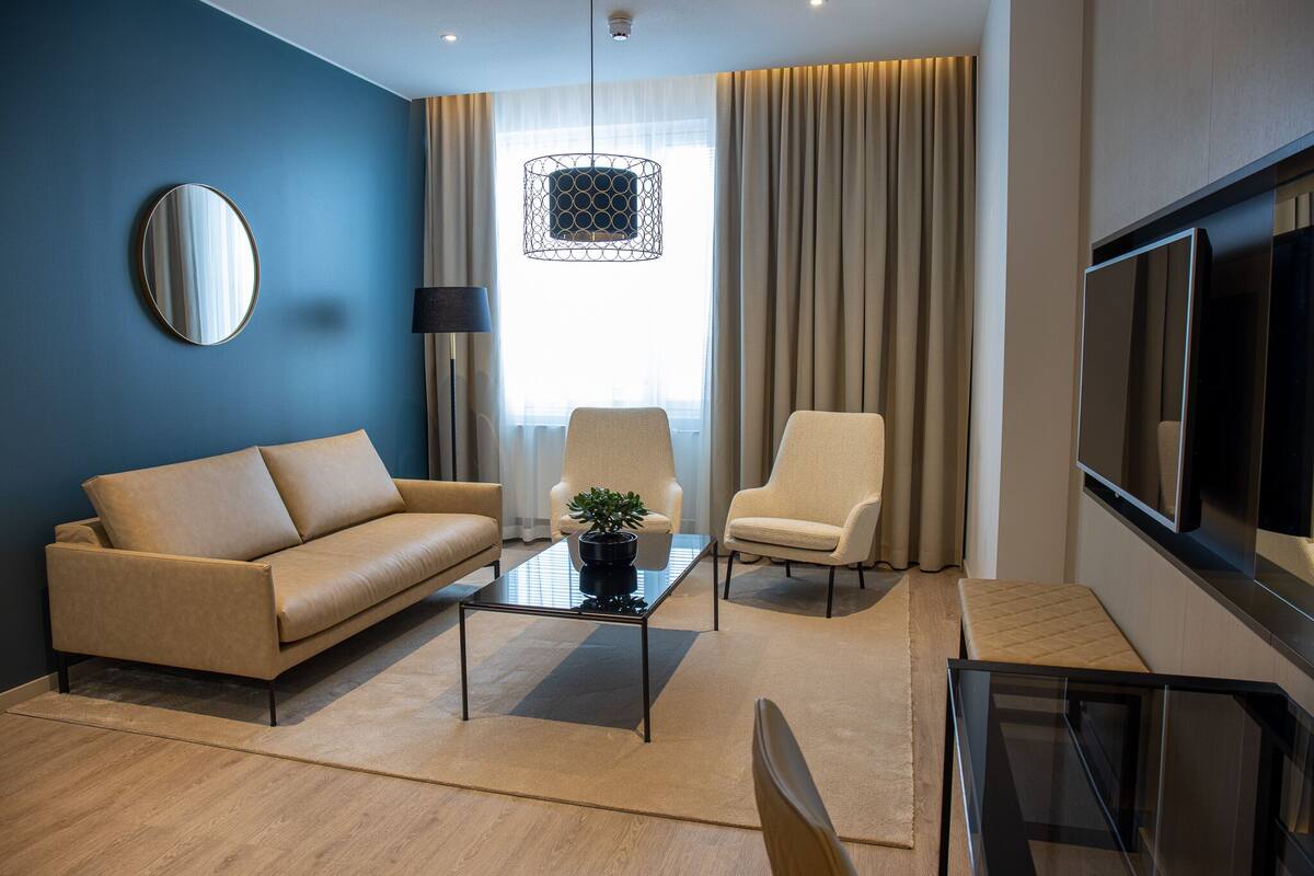 A modern living room with a sofa, armchair, coffee table, and a TV.