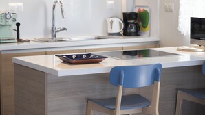Een moderne keuken met een centraal eiland, een spoelbak, een koffiezetapparaat en een waterkoker.