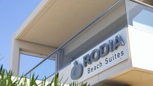 Een bord met 'RODIA Beach Suites', een logo erboven.