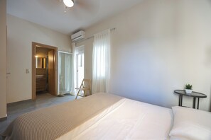 Ein Hotelzimmer mit einem Bett, einem kleinen Tisch mit einer Pflanze, einem Badezimmer mit einem Spiegel und einer Klimaanlage.
