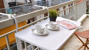 A balcony with a white tray table, two white cups with saucers, a potted plant, and a magazine. - Exarchia a nice and cozy apartment (Athens)