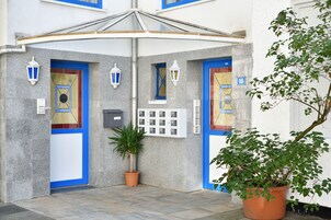 L'ingresso di un edificio con due porte blu, una pianta in vaso e un fiorile a parete.
