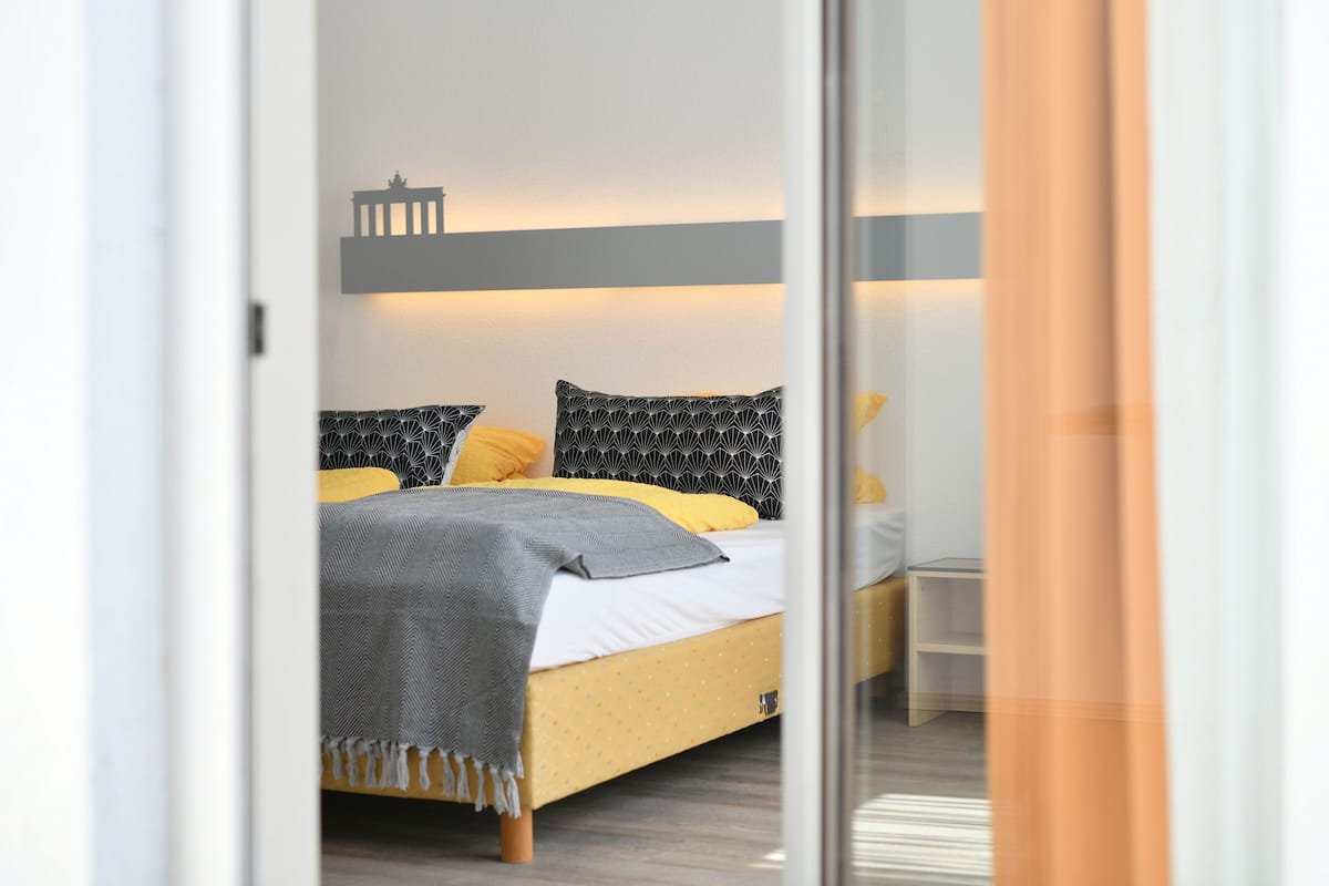 A bedroom with a bed, a nightstand, and a wall-mounted light fixture.