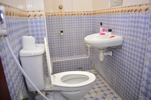 A bathroom with a toilet, sink, and patterned tiles. - Nyali Studio Apartment (Mombasa)
