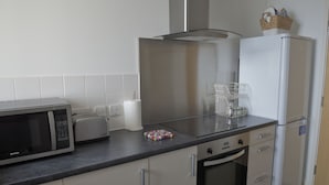 A modern kitchen with a microwave, toaster, and refrigerator. - Toothbrush Apartments Waterfront - Adults Only (Ipswich)