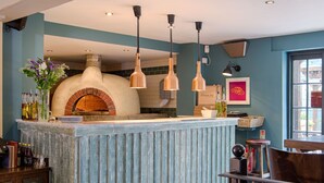 A kitchen with a brick oven, hanging pendant lights, and a window with a view. - The Curious Pig in the Parlour  (Crawley)