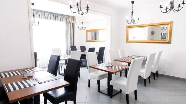 A dining area with a long table, chairs, chandeliers, and a large mirror on the wall. - Astral (Raszyn)