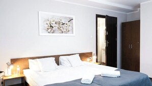 A hotel room with a bed, a nightstand, a framed picture on the wall, and a wardrobe. - Astral (Raszyn)