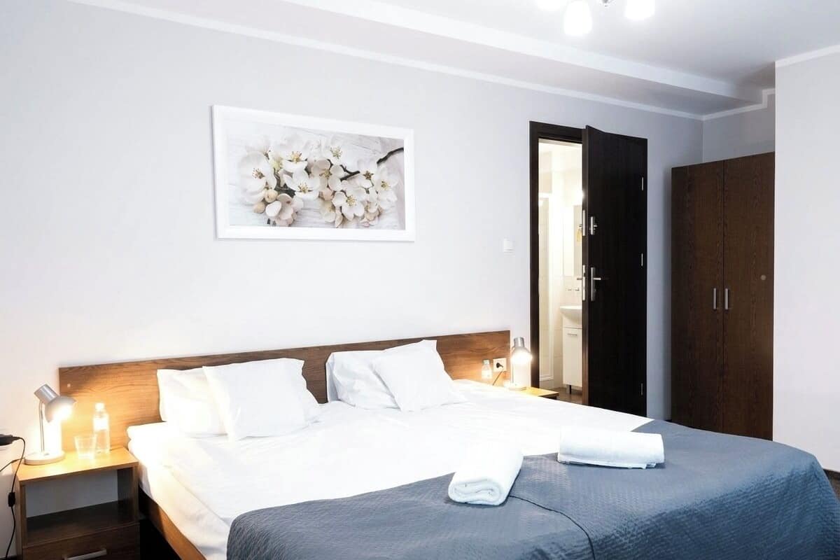 Ein Hotelzimmer mit Bett, Nachttisch, gerahmtem Bild an der Wand und Schrank.