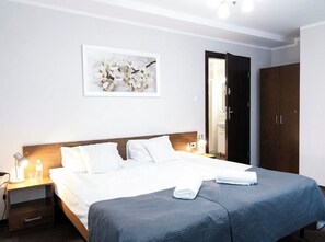 Une chambre d’hôtel avec un lit, une table de chevet, un tableau encadré au mur et une armoire.