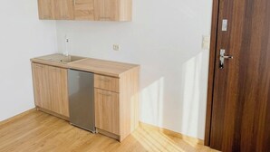 A kitchen with wooden cabinets, a dishwasher, and a wooden door. - Astral (Raszyn)