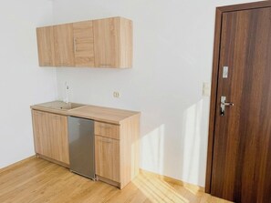 Une cuisine avec des meubles de rangement en bois, un lave-vaisselle et une porte en bois.